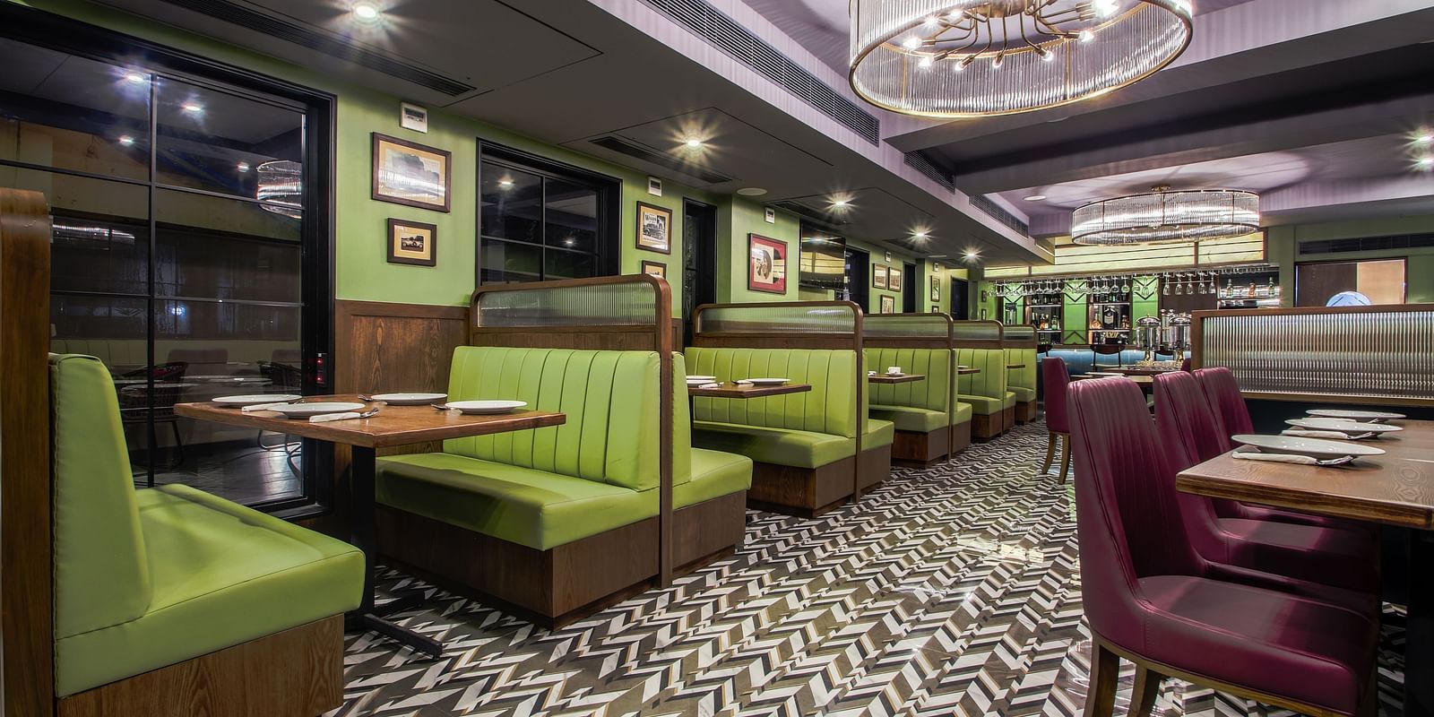 A retro-themed restaurant with green and purple booths, a tiled floor, and vintage-style lighting. 